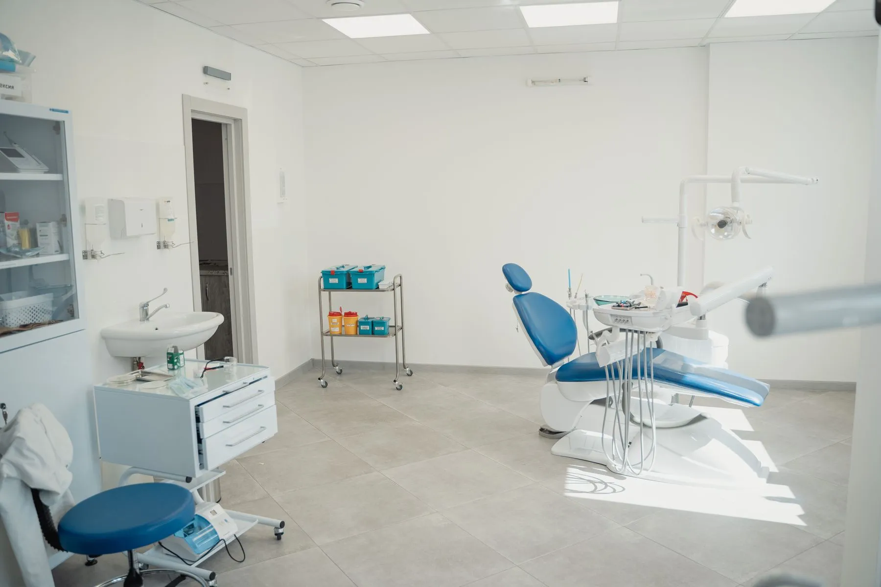 Heller Behandlungsraum mit vorbereiteten Instrumentenablagen
